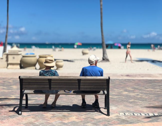 man-and-woman-sitting-on-brown-wooden-bench-1034597 retirement on the beach
